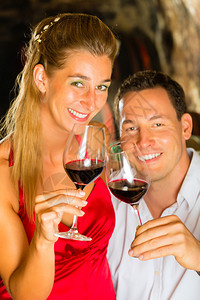一对夫妇男人和女人在地窖里喝红酒在背景图片