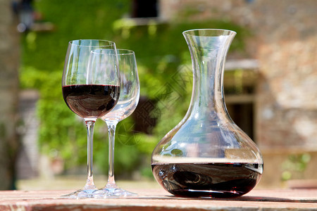 红酒瓶中的红酒和葡萄园中的两个酒杯图片
