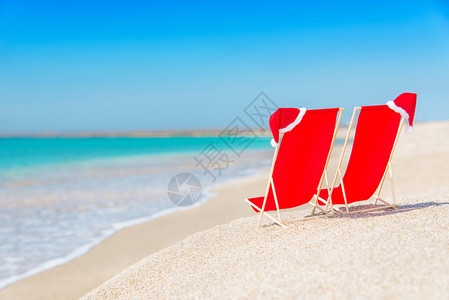 在白色沙滩的躺椅上的圣诞帽图片