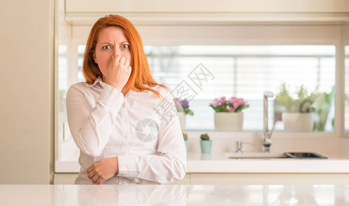 厨房的红发女人闻到一些臭味恶心不可容忍的气味图片