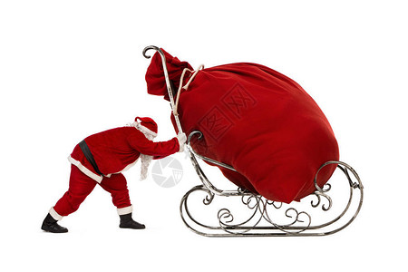 圣诞老人用大袋子推雪橇满的圣诞礼物孤立图片
