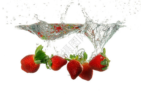 草莓被倾倒在水中白色背景上溅起水花图片