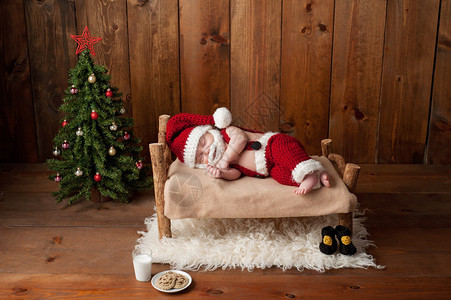 两周大的新生男婴穿着钩针编织的圣诞老人套装图片