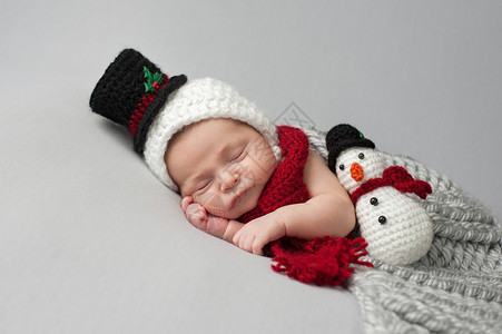 婴儿男孩穿着一个编织的雪人帽子和围巾图片