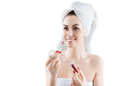 穿着白毛巾洗完澡的迷人女孩正在涂口红图片