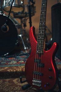 家庭音乐工作室背景上的红色低音吉他图片