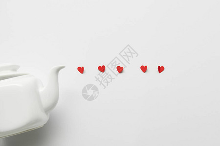 白色背景上的茶壶和红纸切心的顶视图图片