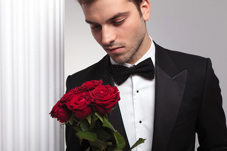 高贵的商人看着红玫瑰花束站在图片