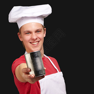 在黑色背景下拿着金属锡罐的年轻厨师的肖像图片