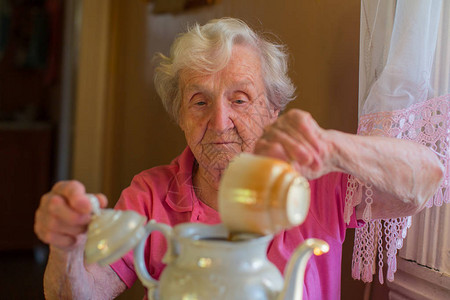 老妇人在水壶里泡茶图片