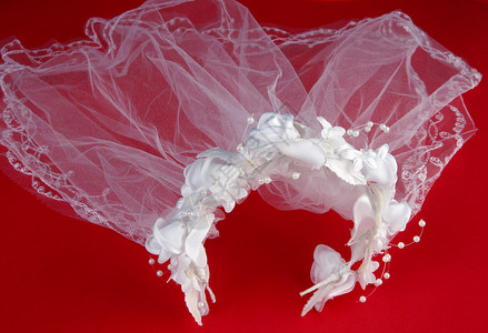 带头饰的白色婚礼面纱在红色背景上图片