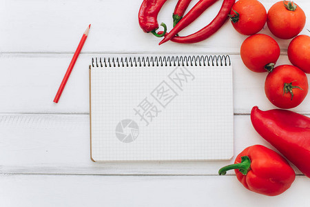 带食谱的笔记本白色木质背景上的红辣椒西红柿和红辣椒图片