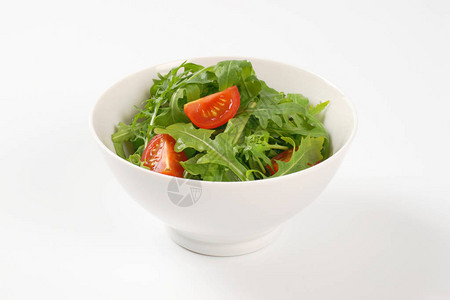 白色背景上的一碗芝麻菜和番茄沙拉图片