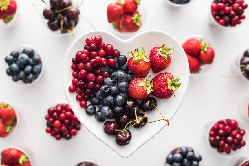 心形盘子上的整个蔓越莓草莓蓝莓和樱桃的顶视图图片