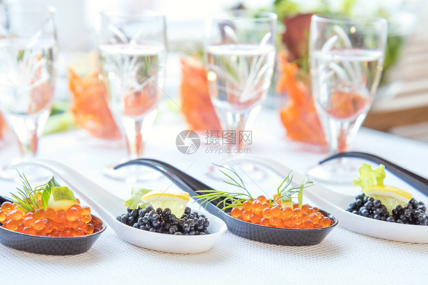 美味的红色和黑色鱼子酱鱼特写在白色桌子上的白色和黑色勺子装饰精美图片
