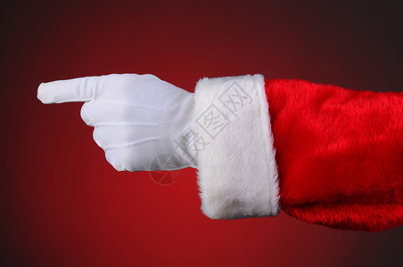 圣诞老人只指着手和臂水平格式在光向暗红背景图片