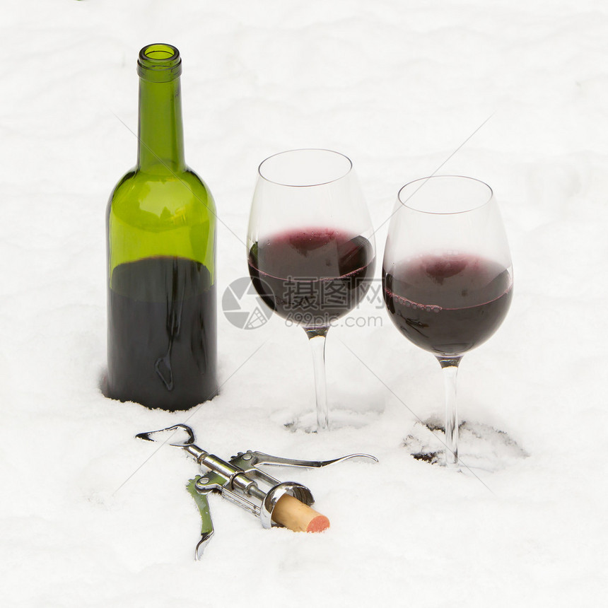 一瓶红酒和杯隔离在冷雪中图片
