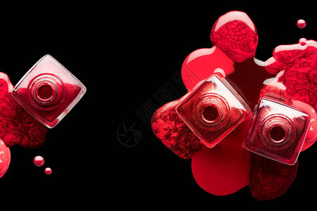 金属红漆或指甲油的美甲和美甲概念巧妙地洒在三个打开的瓶子下面图片