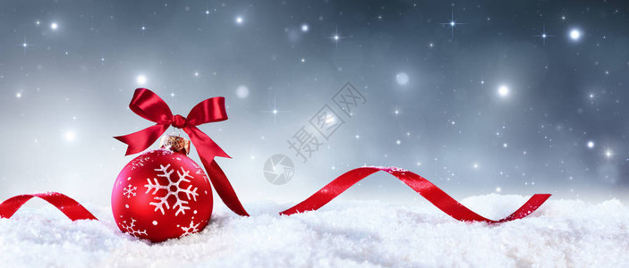 红球弓和丝带在雪上背景图片