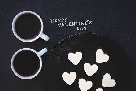 两杯咖啡和巧克力糖果白色的心形刻着快乐的图片