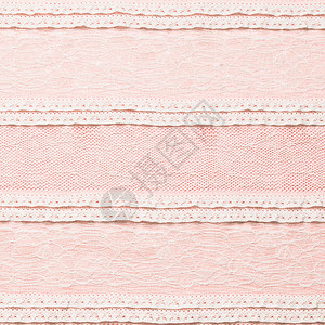 粉红色背景上的象牙色蕾丝面料图片