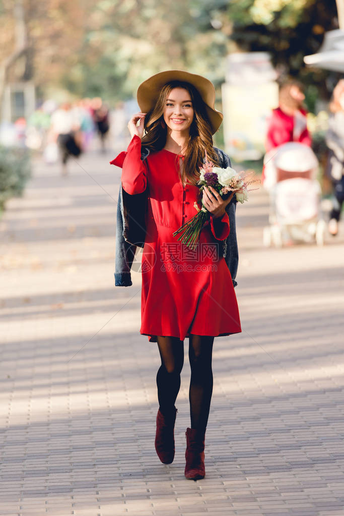 穿着红裙子和戴帽子的快乐女人在公园里图片