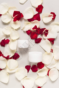 白玫瑰和红玫瑰花瓣上塑料容器中的有机奶油图片
