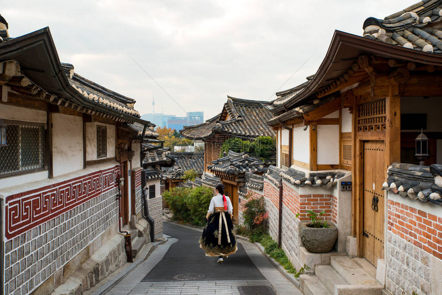 身穿汉博克服装的亚洲妇女背面穿过韩国首尔BukchonHanok村的首尔图片