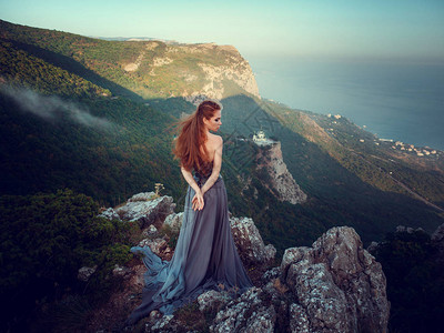 山高雾与神秘的灰色穿着灰色裙子的美丽的姜女人的图片