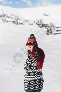 在雪山上穿毛衣和帽子的红发女子冬季肖像图片