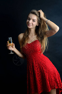 穿着红色裙子参加聚会的年轻女子女孩拿着一杯白葡萄酒或香槟图片