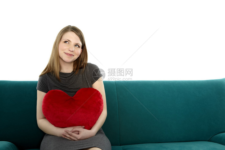 美丽的年轻美女笑着坐在沙发上手里拿着心图片