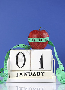 红色苹果和测量胶带在1月的白木旧式日历上背景图片