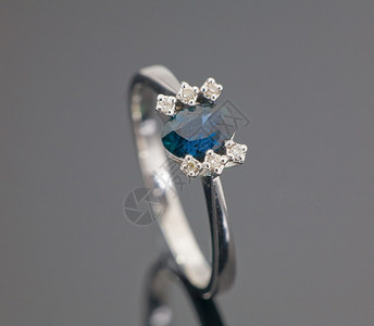 美丽的白金戒指灰色背景上的蓝色宝石图片