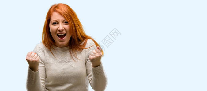 美丽的年轻红发女人快乐和兴奋表达获胜的姿态图片