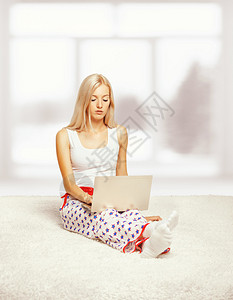 穿着睡衣的年轻金发美女穿着白色整层地毯在窗户旁浏高清图片