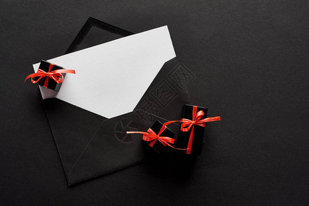 黑色背景的装饰礼品盒附近有空白卡的黑信封顶背景图片