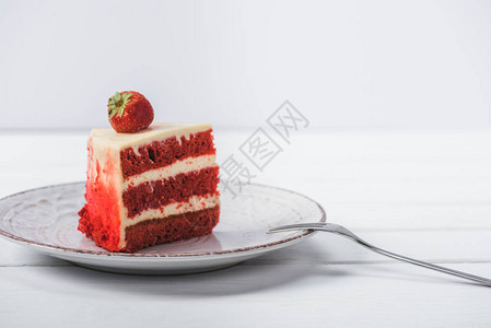 一块红色蛋糕装饰着草莓在沙图片