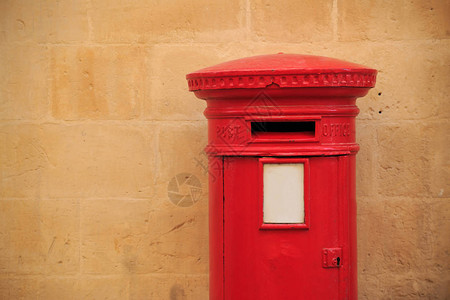 红色的传统古老的英国信箱接收信件的邮箱背景的浅橙色石灰墙文本空图片