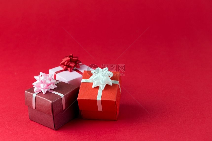三个装有丝带和弓的礼物盒在红图片