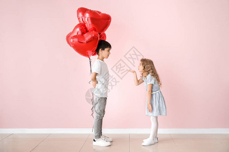 小女孩用彩色背景的气球为可爱的男孩送吻情图片