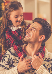 英俊的年轻父亲和他的迷人的小女儿在家庆祝图片