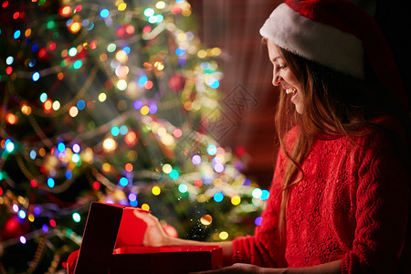 圣诞树帽的欢乐女人打开魔盒带着圣诞礼物和闪图片