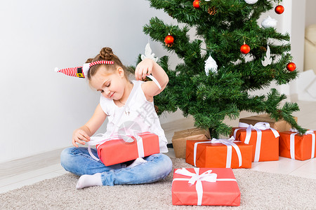 小孩打开Xmas礼物圣诞树下的图片