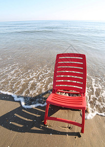 红色的椅子沐浴在蓝色大海的波涛中高清图片