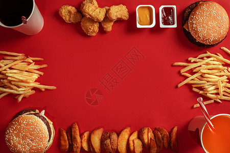 红色背景上的两个汉堡包和炸薯条酱汁和快餐汉堡配鸡块顶视图图片