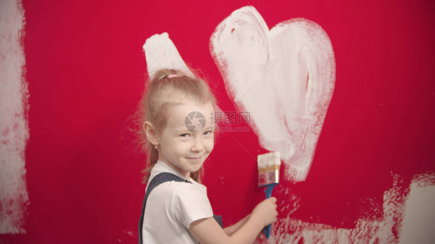 一个小女孩在红墙上画着白图片
