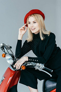 时髦的漂亮女人仰赖古老的骑摩托车图片