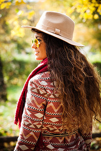 戴着帽子太阳镜大衣和红围巾的长卷发微笑的年轻女子图片