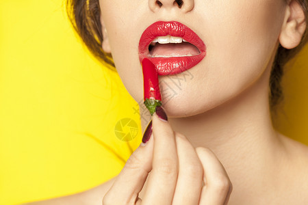 年轻女使用红辣椒作为背景图片